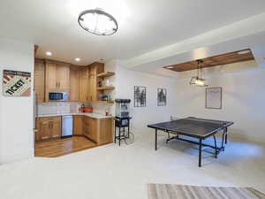 Kitchen featuring backsplash, recessed lighting, open shelves, brown cabinetry, and light colored carpet