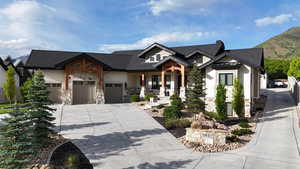 View of front of house featuring stone siding, driveway, a garage, and covered porch