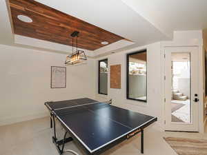 Rec room with a raised ceiling, light colored carpet, wooden ceiling, and recessed lighting