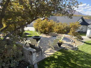 View of green lawn featuring a patio area, a mountain view, and an outdoor fire pit