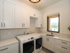 Laundry room featuring independent washer and dryer, cabinet space, and dark tile patterned flooring