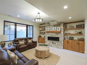 Living area with carpet flooring, a stone fireplace, and recessed lighting