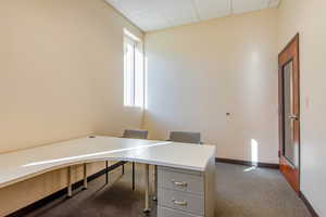 Office area with dark colored carpet and a paneled ceiling
