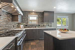 Kitchen featuring double oven range, dark brown cabinetry, extractor fan, plenty of natural light, and recessed lighting