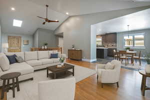 Living area featuring light wood finished floors, recessed lighting, a ceiling fan, a skylight, and high vaulted ceiling