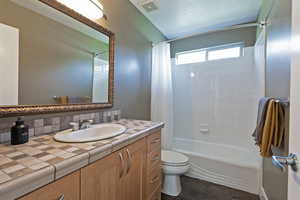 Full bathroom with shower / bath combo with shower curtain, vanity, and decorative backsplash