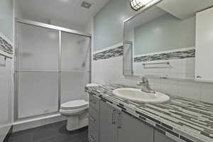 Bathroom with vanity, a shower stall, and tile walls