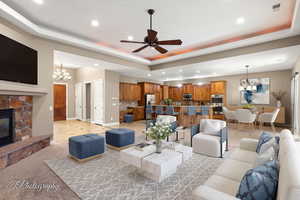 Living area with a chandelier, a raised ceiling, recessed lighting, and a stone fireplace