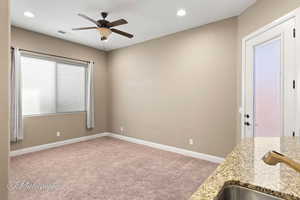 Kitchen with light carpet, ceiling fan, recessed lighting, and light stone counters