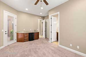 Bar with light carpet, a ceiling fan, recessed lighting, light stone counters, and brown cabinetry