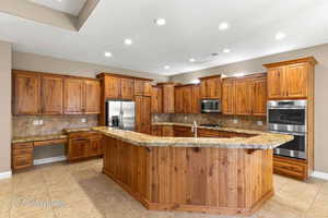 Kitchen featuring tasteful backsplash, brown cabinetry, recessed lighting, light stone countertops, and stainless steel appliances