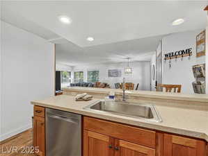 Kitchen featuring stainless steel dishwasher, brown cabinets, light wood-style floors, open floor plan, and recessed lighting