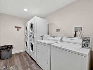 Community laundry featuring dark wood-style floors, washer and clothes dryer, stacked washing machine and dryer, and recessed lighting