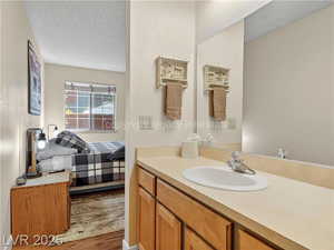 Ensuite bathroom featuring a textured ceiling, vanity, and wood finished floors