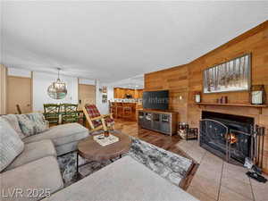 Living area featuring wood walls, a textured ceiling, a warm lit fireplace, and wood finished floors