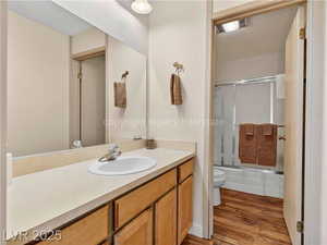 Bathroom featuring bath / shower combo with glass door, vanity, and light wood-type flooring