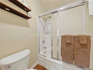 Bathroom with shower / bath combination with glass door and wood finished floors