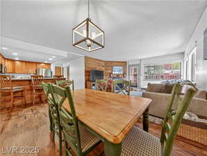 Dining area with wood walls, wood finished floors, a textured ceiling, and a chandelier