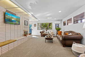 Carpeted living room with recessed lighting and a brick fireplace