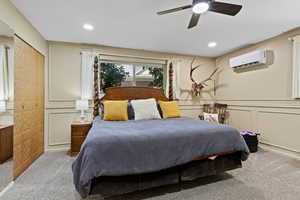Bedroom featuring light colored carpet, ceiling fan, recessed lighting, a decorative wall, and a wall unit AC
