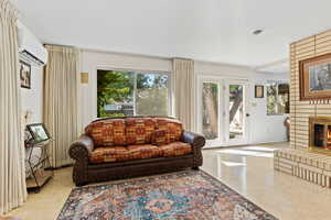 Living room featuring a wall mounted AC and a brick fireplace