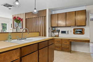 Kitchen featuring brown cabinets, light countertops, and hanging light fixtures