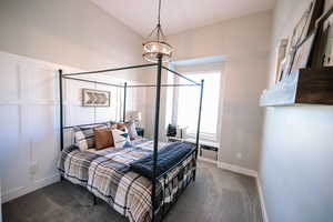 Carpeted bedroom with lofted ceiling and baseboards