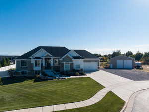 Craftsman-style house with a detached garage, board and batten siding, stone siding, and driveway
