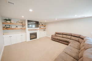 Living room with light carpet, a glass covered fireplace, and recessed lighting