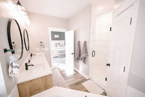 Full bath featuring a shower stall, light wood-style floors, double vanity, and recessed lighting