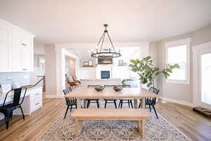 Dining area featuring light wood finished floors, built in desk, and a glass covered fireplace