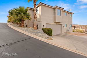 View of front facade featuring a garage, stucco siding, a tiled roof, and driveway