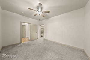 Spare room featuring light colored carpet, a ceiling fan, and a textured ceiling