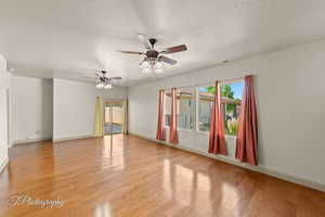 Empty room with light wood-style floors, a textured ceiling, and a ceiling fan