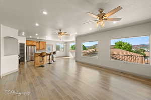 Living area featuring light wood-style flooring, recessed lighting, ceiling fan, and a textured ceiling