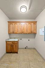 Laundry area with cabinet space, washer hookup, gas dryer hookup, hookup for an electric dryer, and a textured ceiling