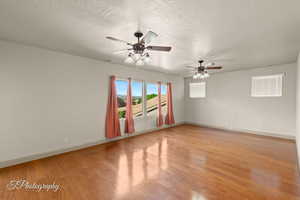Spare room featuring light wood-style flooring, a textured ceiling, and a ceiling fan