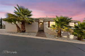 View of front of house with stucco siding and a tiled roof