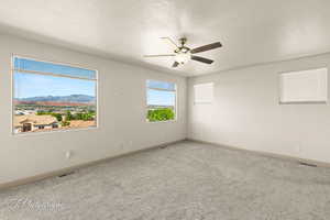 Spare room featuring carpet floors, a textured ceiling, and a ceiling fan
