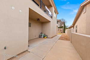 View of side of property featuring stucco siding, a balcony, and a patio