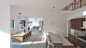 Kitchen with pendant lighting, stainless steel electric range oven, dark brown cabinets, a ceiling fan, and a kitchen bar