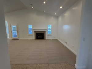 Unfurnished great room featuring high vaulted ceiling, light carpet, a tile fireplace, light tile patterned floors, and recessed lighting