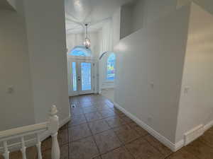 Entryway with light tile patterned floors, a high ceiling, arched walkways, and a chandelier