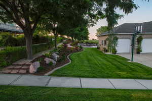 View of grassy yard with concrete driveway and an attached garage