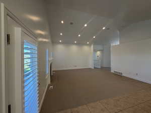 Carpeted empty room with a fireplace, recessed lighting, lofted ceiling, and tile-patterned floors