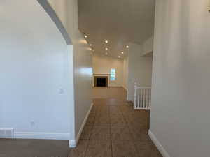 Corridor with recessed lighting, light tile patterned floors, arched walkways, and light colored carpet
