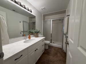 Bathroom with vanity, a stall shower, and dark tile patterned floors