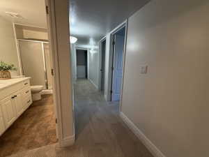 Corridor featuring a textured ceiling and dark colored carpet