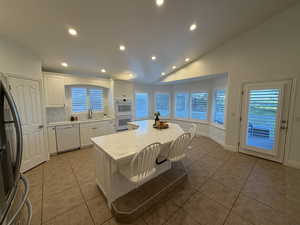 Kitchen featuring recessed lighting, white cabinetry, light tile patterned floors, white appliances, and a center island