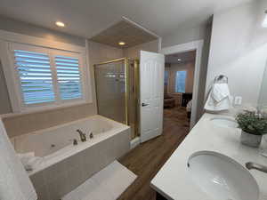 Full bathroom featuring ensuite bath, a shower stall, dark wood-style floors, a jetted tub, and double vanity
